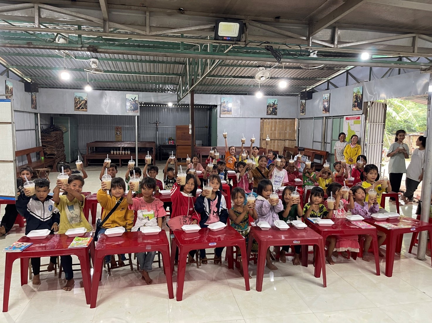 A group of children sitting at tables in a roomDescription automatically generated