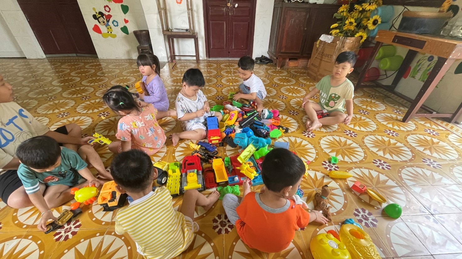 A group of children sitting on the floor playing with toysDescription automatically generated