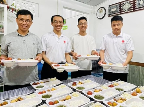 A group of men holding food in containersDescription automatically generated