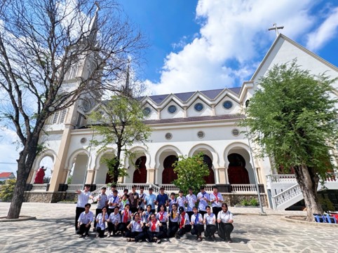 A group of people posing for a picture in front of a churchDescription automatically generated